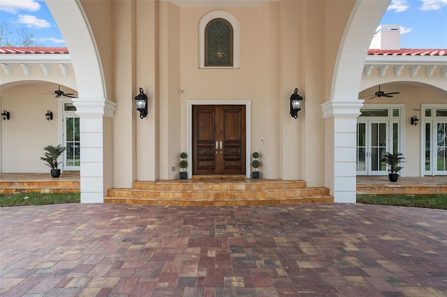 view of exterior entry featuring ceiling fan and french doors