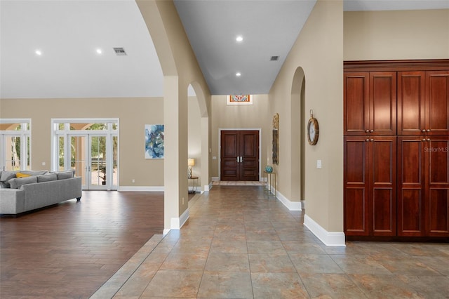 entrance foyer with light wood-type flooring, a high ceiling, and french doors