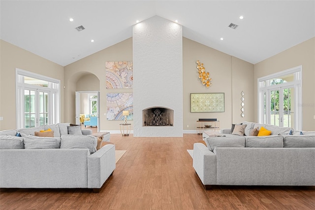 living room featuring a fireplace, french doors, high vaulted ceiling, and light hardwood / wood-style flooring