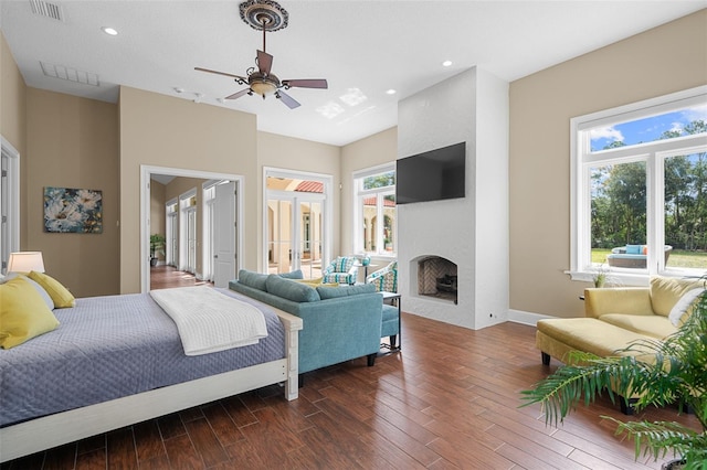 bedroom with a large fireplace, ceiling fan, dark hardwood / wood-style flooring, and french doors