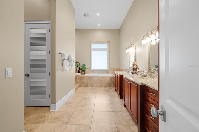 bathroom featuring tile patterned floors, a relaxing tiled tub, and vanity