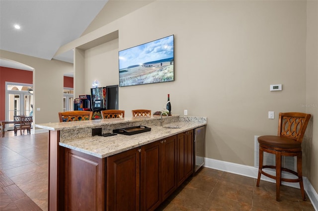 bar with french doors, sink, light stone counters, vaulted ceiling, and dark tile patterned flooring