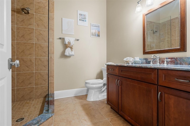 bathroom with tile patterned floors, vanity, toilet, and a tile shower