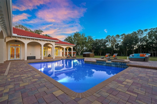 pool at dusk with an outdoor living space, french doors, ceiling fan, an in ground hot tub, and a patio area