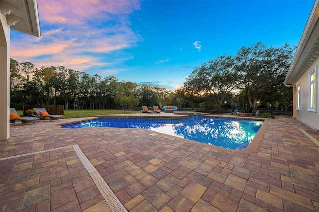 pool at dusk featuring a patio