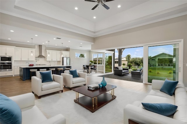 living room with hardwood / wood-style floors, ceiling fan, a towering ceiling, and crown molding