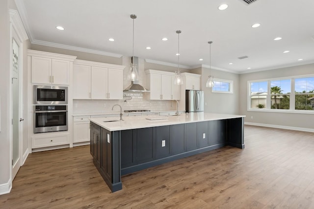 kitchen with white cabinetry, pendant lighting, wall chimney range hood, and appliances with stainless steel finishes