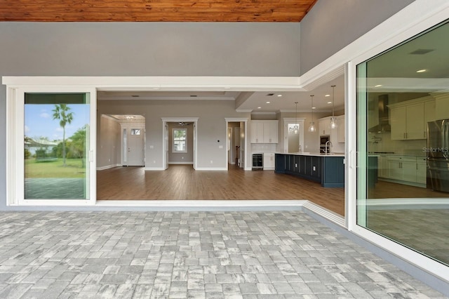 unfurnished living room featuring wine cooler, hardwood / wood-style floors, and sink