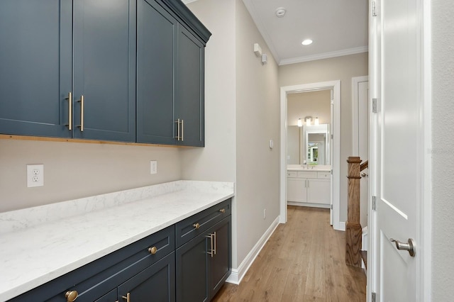 interior space featuring light stone countertops, light hardwood / wood-style flooring, ornamental molding, and sink