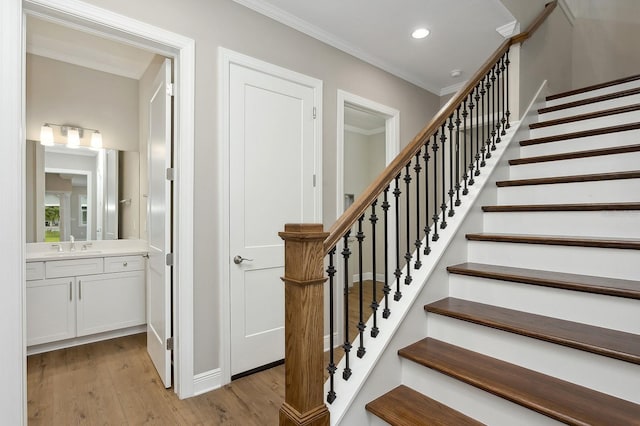 stairway with crown molding, sink, and hardwood / wood-style flooring