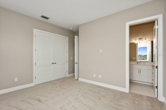 unfurnished bedroom featuring light colored carpet, sink, and connected bathroom