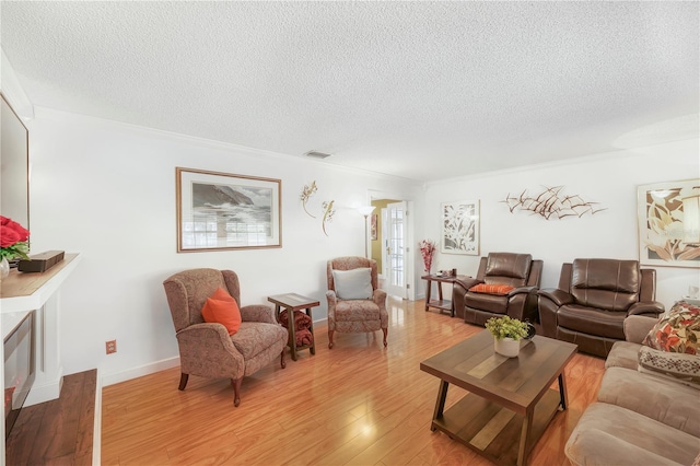 living room with a textured ceiling, crown molding, and light hardwood / wood-style floors