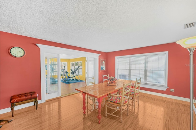 dining space featuring a textured ceiling, light wood-type flooring, and a wealth of natural light