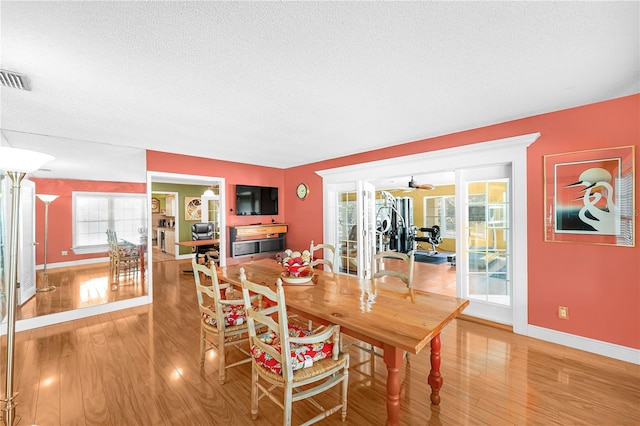 dining area featuring a textured ceiling, ceiling fan, and light wood-type flooring