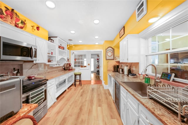 kitchen featuring sink, white cabinets, light hardwood / wood-style flooring, stainless steel appliances, and tasteful backsplash