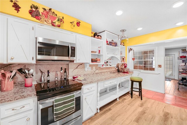 kitchen with light stone countertops, backsplash, appliances with stainless steel finishes, light tile floors, and white cabinets