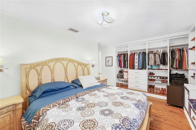 bedroom with light hardwood / wood-style floors, a textured ceiling, and a closet