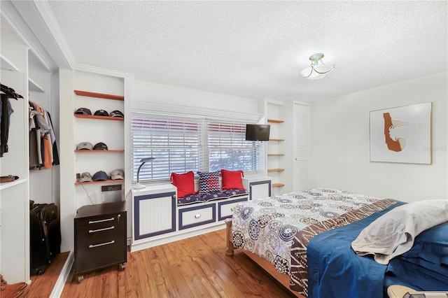 bedroom with a closet, ornamental molding, light hardwood / wood-style flooring, and a textured ceiling