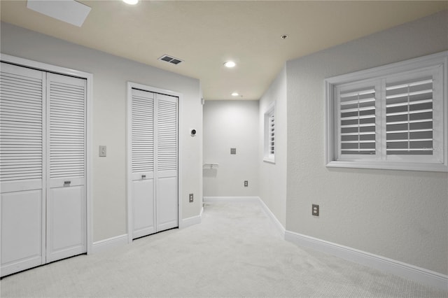 interior space with light colored carpet and two closets