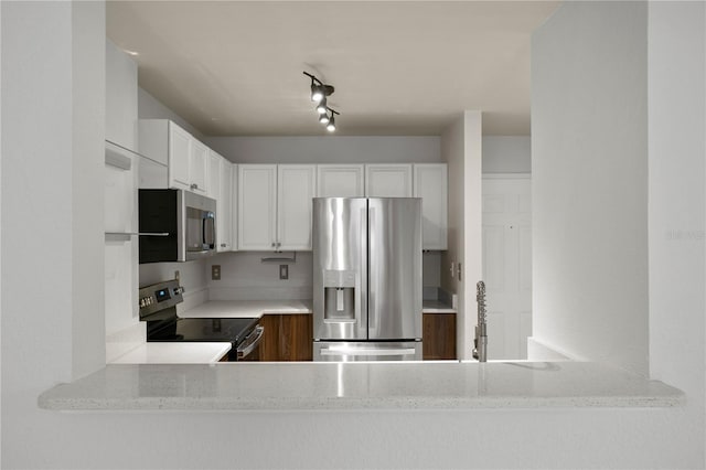 kitchen featuring stainless steel appliances, white cabinetry, and light stone counters