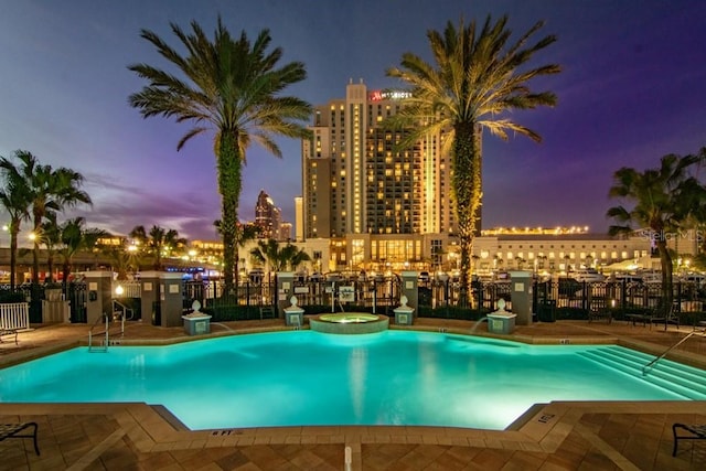 pool at dusk with a community hot tub and a patio