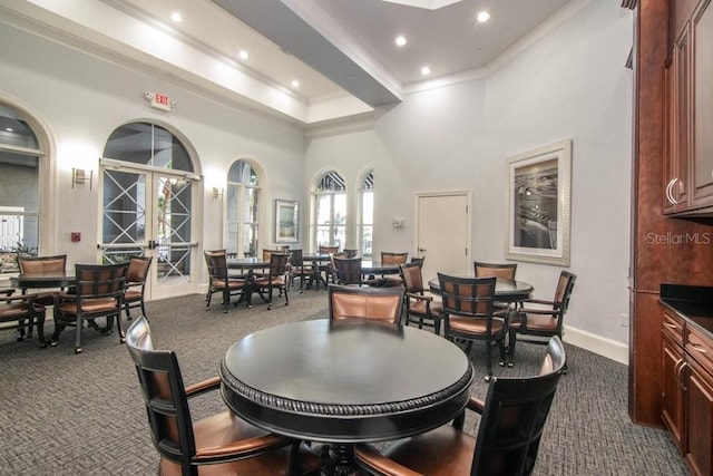 carpeted dining room with french doors, a towering ceiling, and ornamental molding