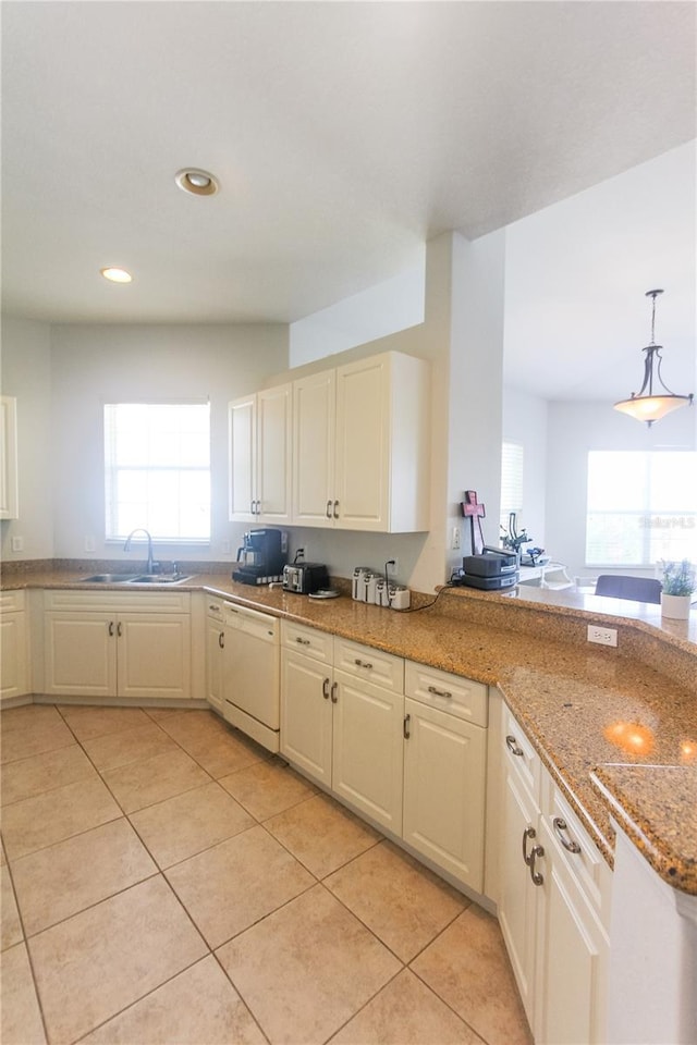 kitchen featuring white dishwasher, sink, hanging light fixtures, light stone countertops, and light tile patterned floors