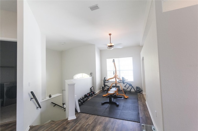 workout area featuring washer / clothes dryer, ceiling fan, and dark wood-type flooring