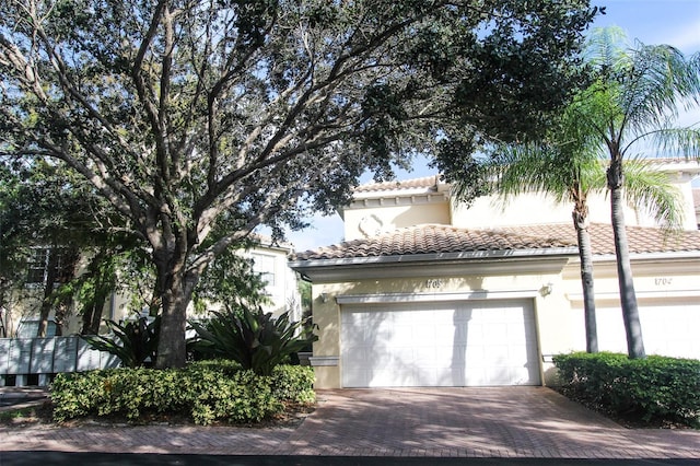 view of front of house featuring a tile roof, decorative driveway, a garage, and stucco siding