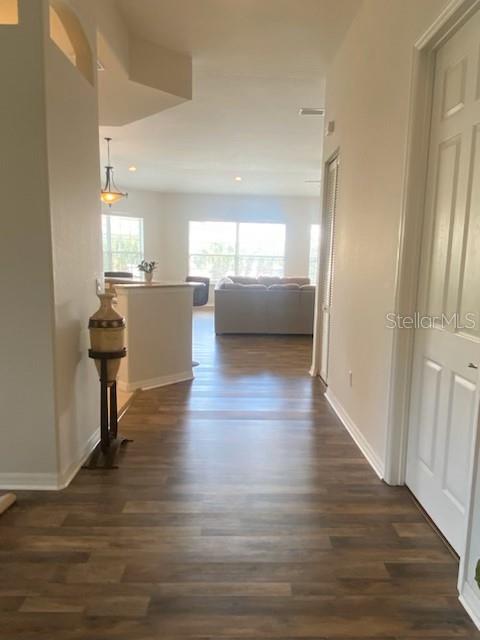 hallway featuring recessed lighting, baseboards, and dark wood-style flooring