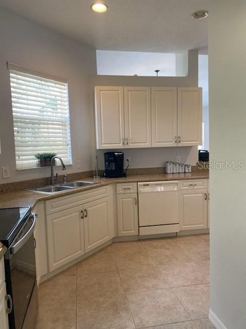 kitchen featuring light tile patterned floors, white dishwasher, a sink, white cabinets, and black range with electric stovetop