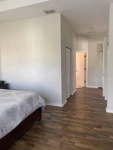 bedroom with visible vents, baseboards, and dark wood-type flooring