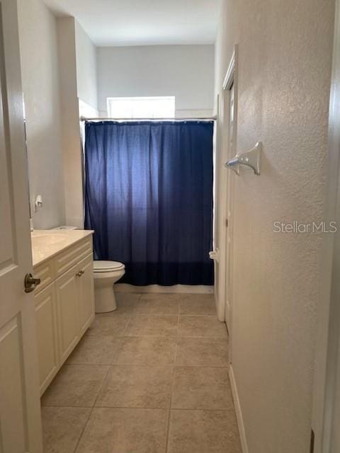 bathroom featuring tile patterned flooring, vanity, toilet, and curtained shower