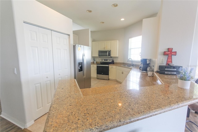 kitchen with sink, appliances with stainless steel finishes, cream cabinetry, light tile patterned flooring, and kitchen peninsula