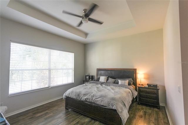 bedroom featuring a raised ceiling, ceiling fan, and dark hardwood / wood-style flooring