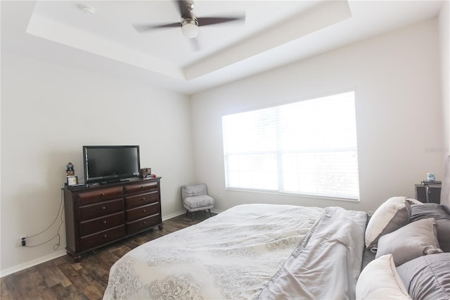 bedroom featuring a raised ceiling, ceiling fan, and dark wood-type flooring