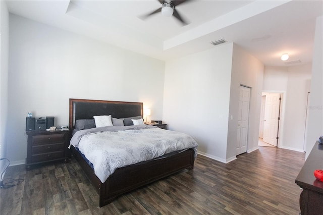 bedroom with dark hardwood / wood-style flooring, a raised ceiling, and ceiling fan