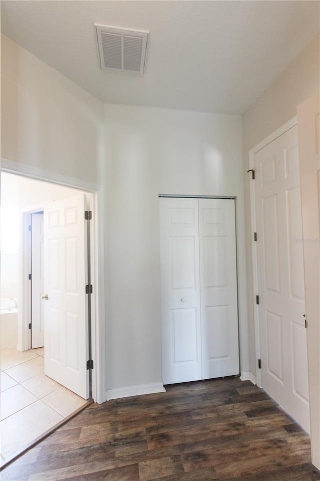 unfurnished bedroom with ensuite bathroom, dark wood-type flooring, and a closet