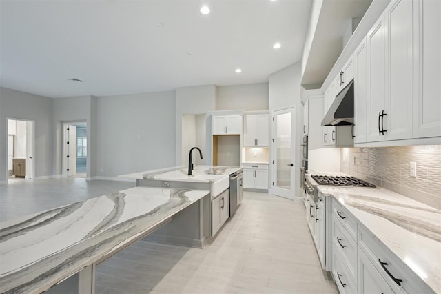 kitchen featuring white cabinets, sink, light hardwood / wood-style flooring, light stone countertops, and decorative backsplash