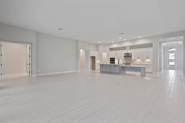 unfurnished living room with light wood-type flooring and sink