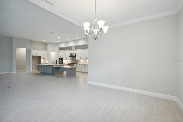 kitchen with an island with sink, light hardwood / wood-style floors, an inviting chandelier, and decorative light fixtures