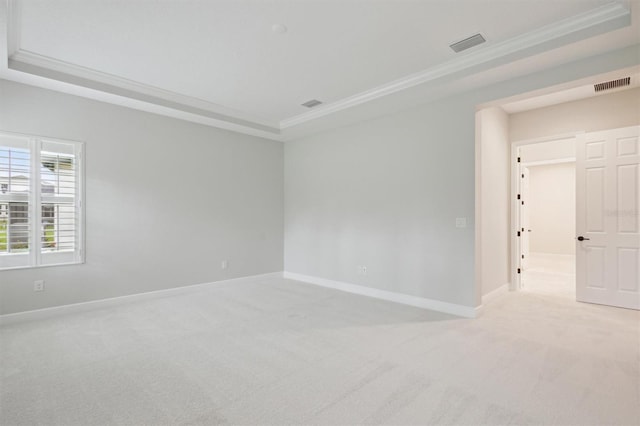 unfurnished room featuring crown molding, a tray ceiling, and light colored carpet