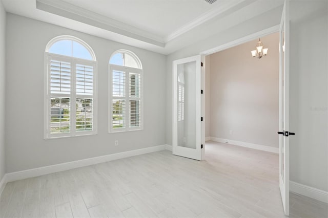 unfurnished room featuring a healthy amount of sunlight, crown molding, an inviting chandelier, and light hardwood / wood-style flooring