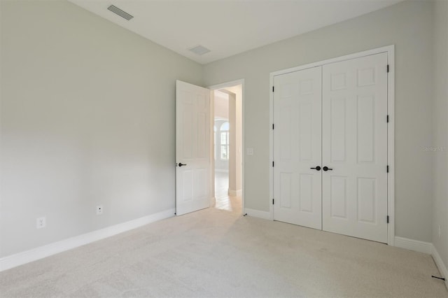 unfurnished bedroom with light colored carpet and a closet