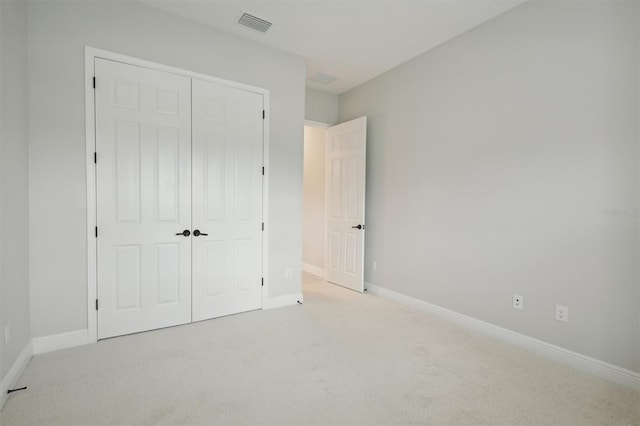 unfurnished bedroom with light carpet and a closet