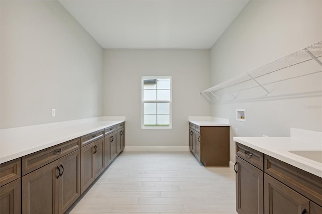 laundry area featuring light wood-type flooring, washer hookup, and cabinets