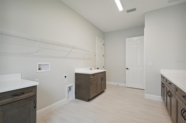 laundry area featuring cabinets, light wood-type flooring, sink, electric dryer hookup, and hookup for a washing machine