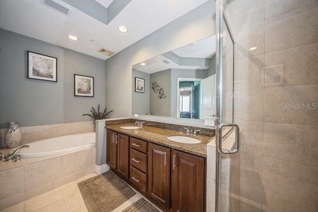 bathroom with tiled bath, dual vanity, and tile patterned floors