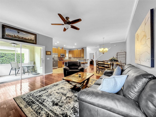 living room featuring light hardwood / wood-style flooring, ceiling fan with notable chandelier, and ornamental molding