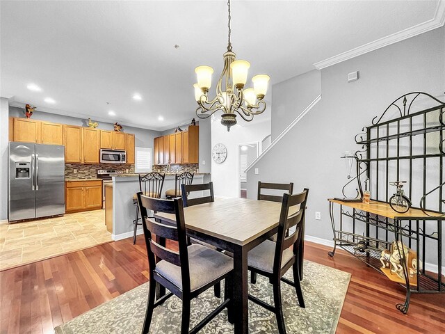 dining area with light hardwood / wood-style flooring, a chandelier, and ornamental molding